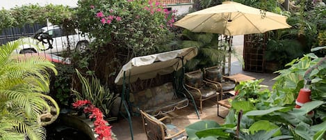 A patio area with outdoor furniture, a small water feature, and lush greenery.