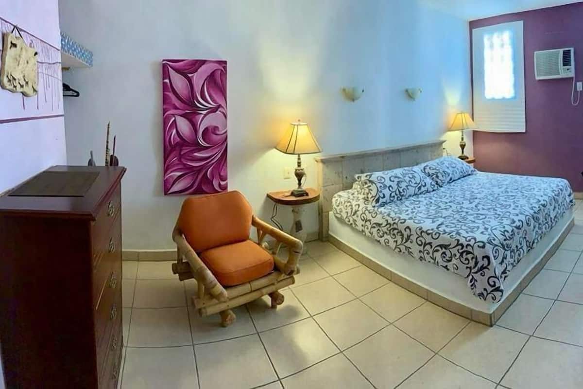 Une chambre à coucher avec un lit, une chaise, un bureau et une lampe.