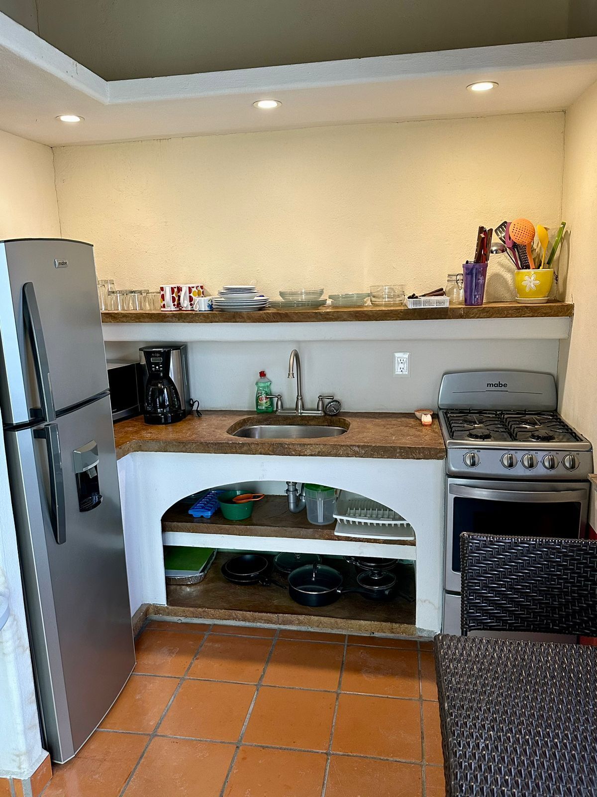 A compact kitchen with a refrigerator, coffee maker, sink, stove, and oven.