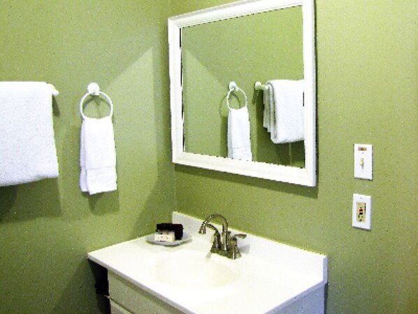 A bathroom with a white sink, a mirror, and two towel rings on the wall. - The Olde Mill Inn Bed & Breakfast (Cumberland Gap)