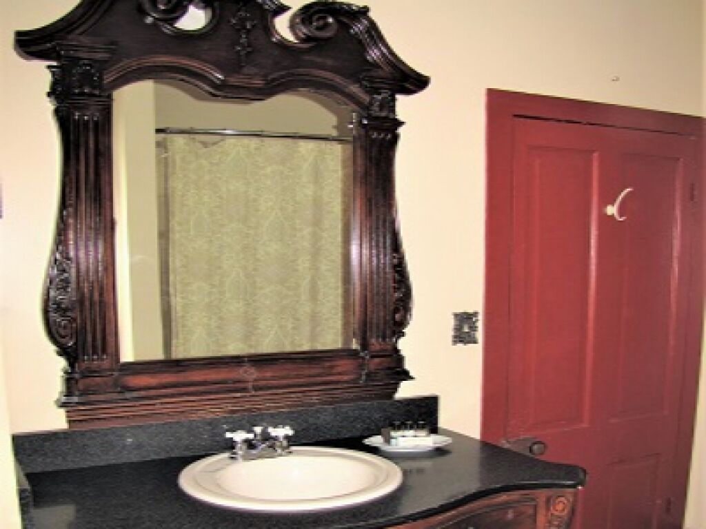 A bathroom with a large mirror, a sink, and a red door.