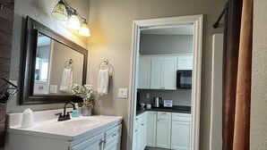 A bathroom with a large mirror, a sink, and a towel rack. - The Olde Mill Inn Bed & Breakfast (Cumberland Gap)