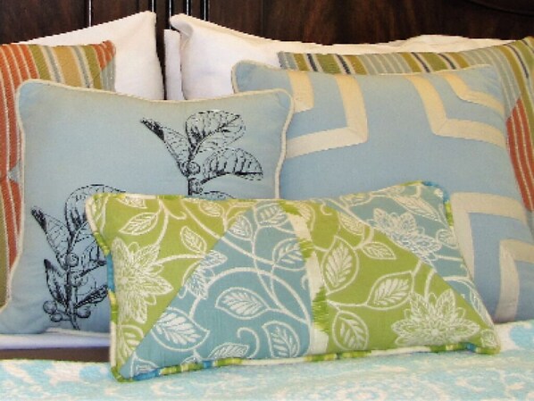 Una cama con muchos almohadones de diversos diseños y colores.