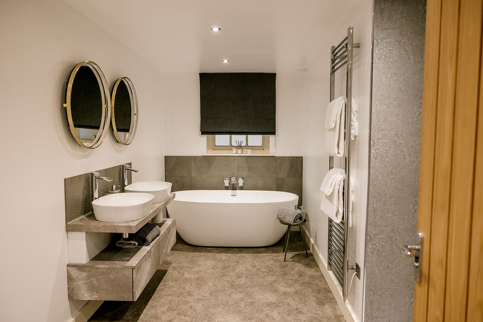 A modern bathroom with two sinks, a freestanding bathtub, and a towel rack.
