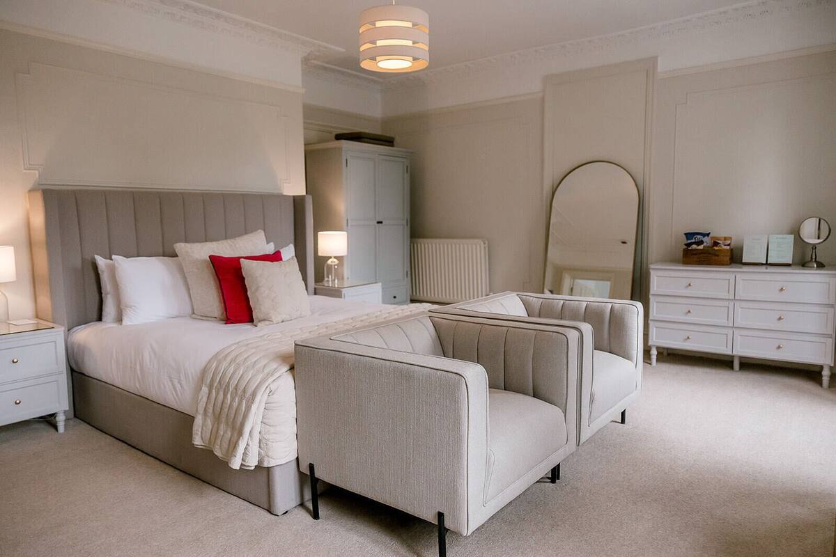 A bedroom with a bed, nightstands, a dresser, and a mirror.