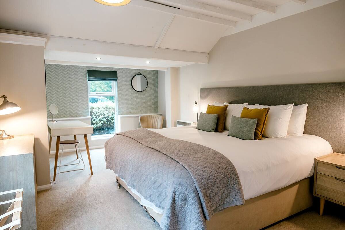 A bedroom with a large bed, bedside tables, a desk, and a chair.