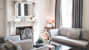 Un salon avec une cheminée, un canapé, une table basse et un miroir.
