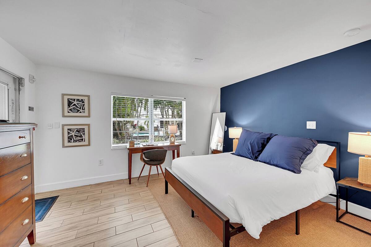 A bedroom with a bed, bedside tables, a dresser, a desk, and a chair.