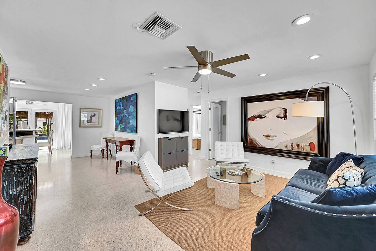 A modern living room with a sofa, coffee table, and a television. There is a ceiling fan and recessed lighting.