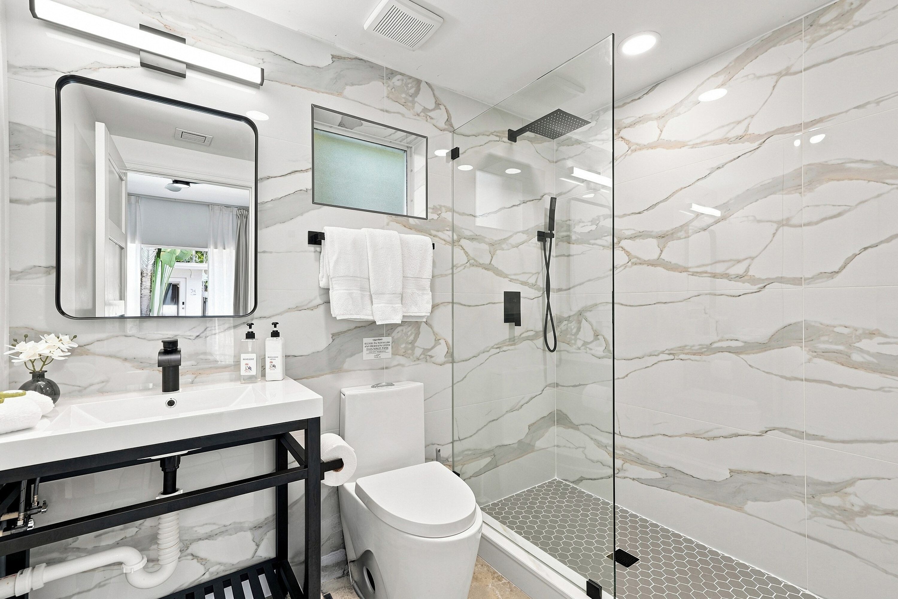 Un baño con ducha de vidrio, lavamanos blanco y un inodoro.