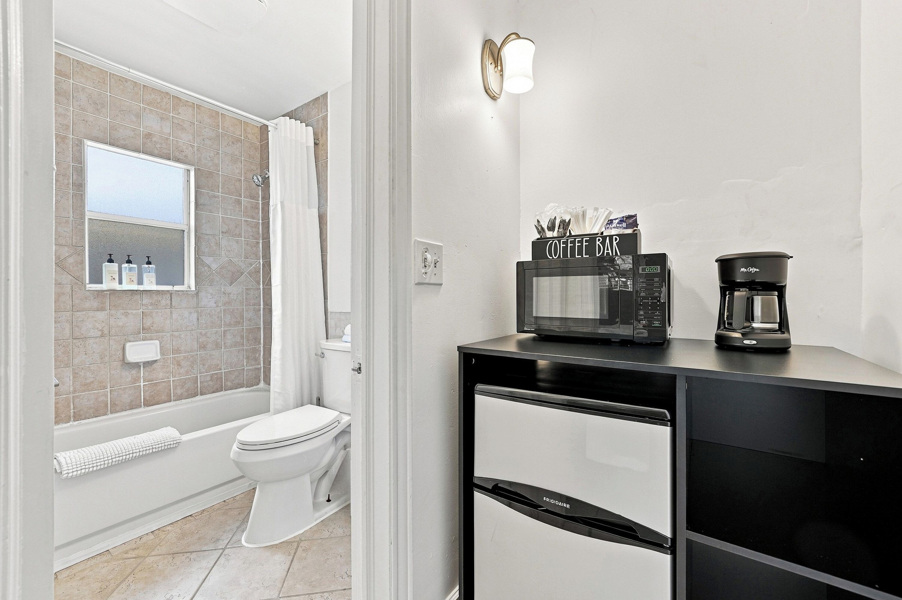 A modern bathroom with a toilet, shower, and a coffee bar.