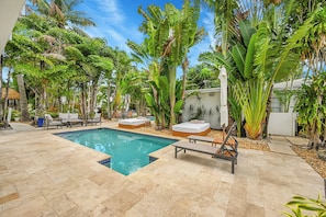 A pool area with lounge chairs, a small pool, and tropical plants. - Inn On The Drive (Adults Only) (Wilton Manors)