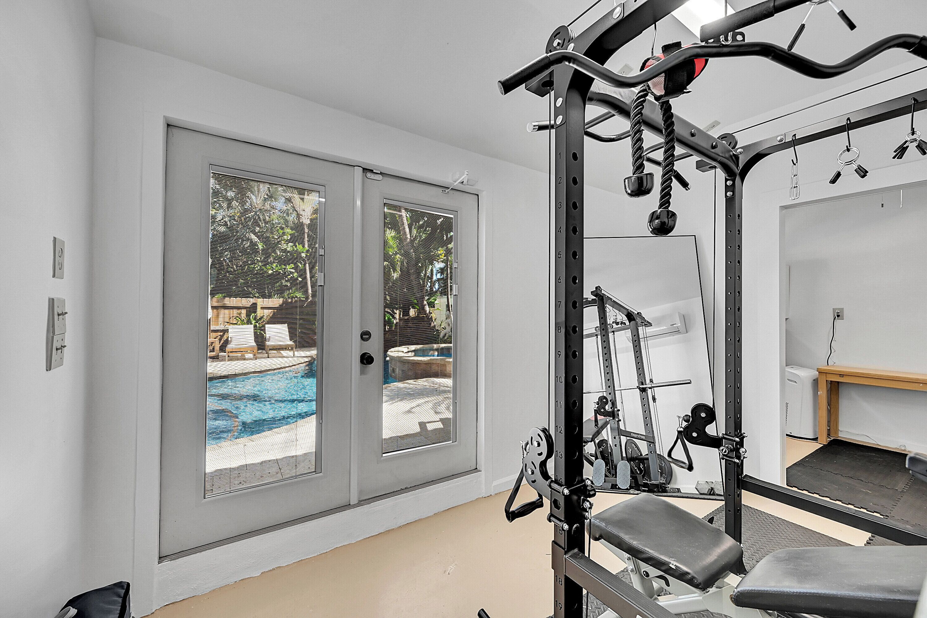 Un gimnasio en casa con barra de dominadas, prensa de banca y estante para pesas.