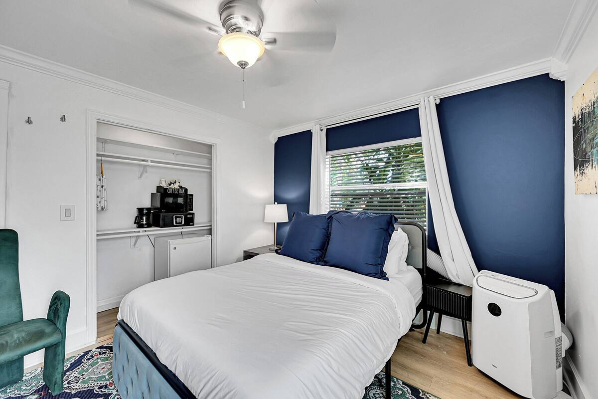 A bedroom with a bed, a desk, a chair, and a ceiling fan.