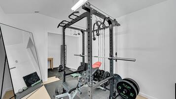A home gym with a squat rack, bench press, and various weight plates.