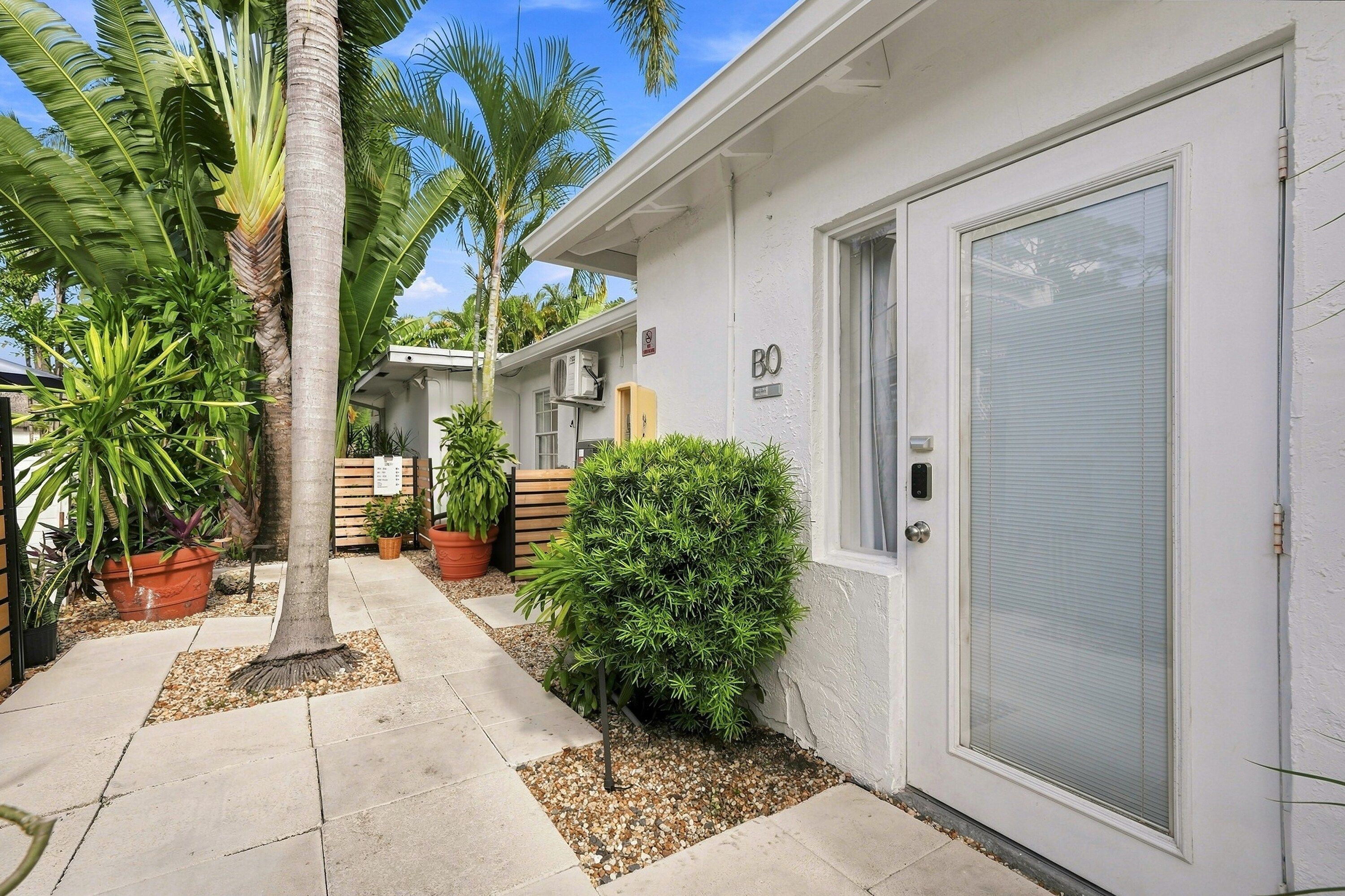 A residential building with a gated entrance, a covered porch, and a variety of potted plants.