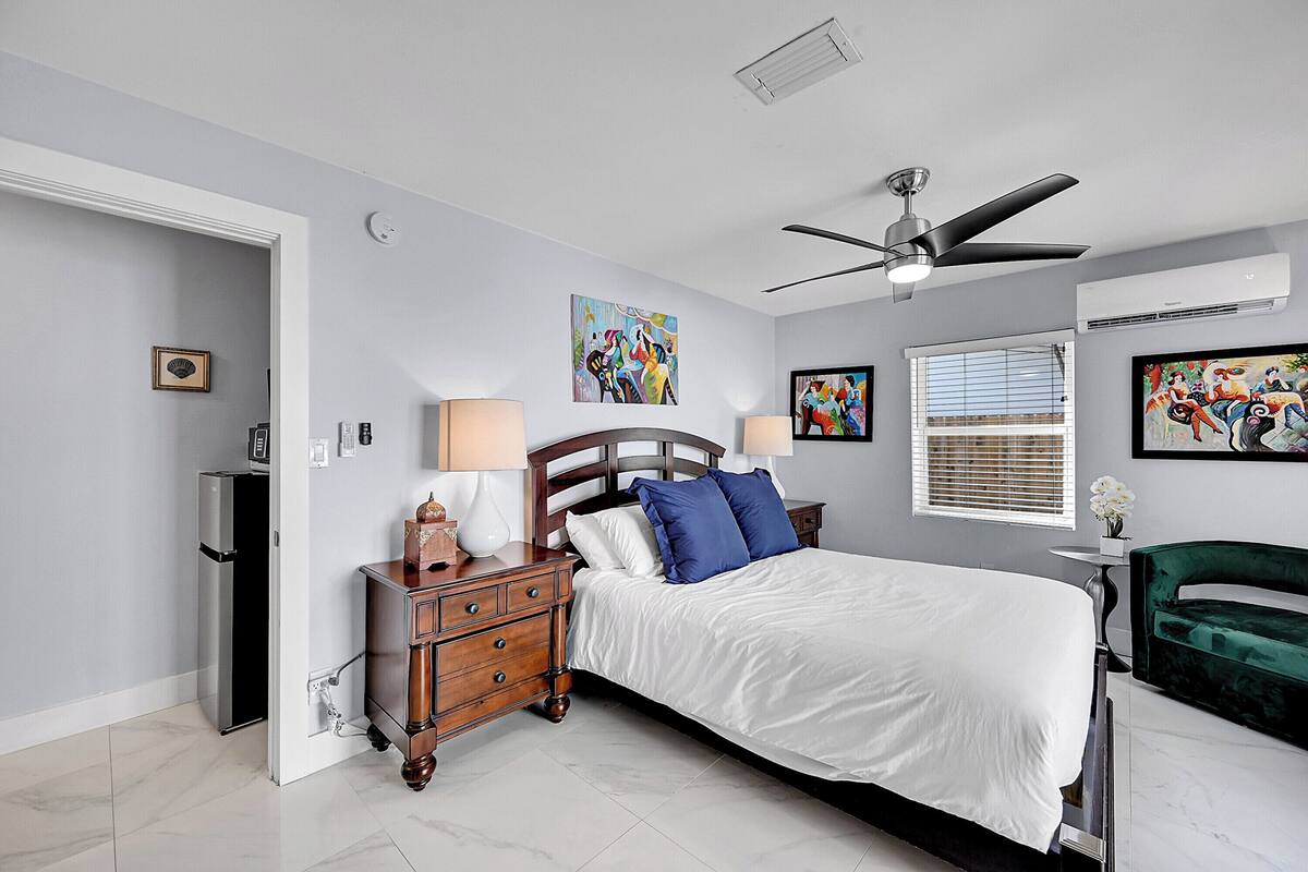 A bedroom with a bed, nightstands, a dresser, a ceiling fan, and artwork on the walls.