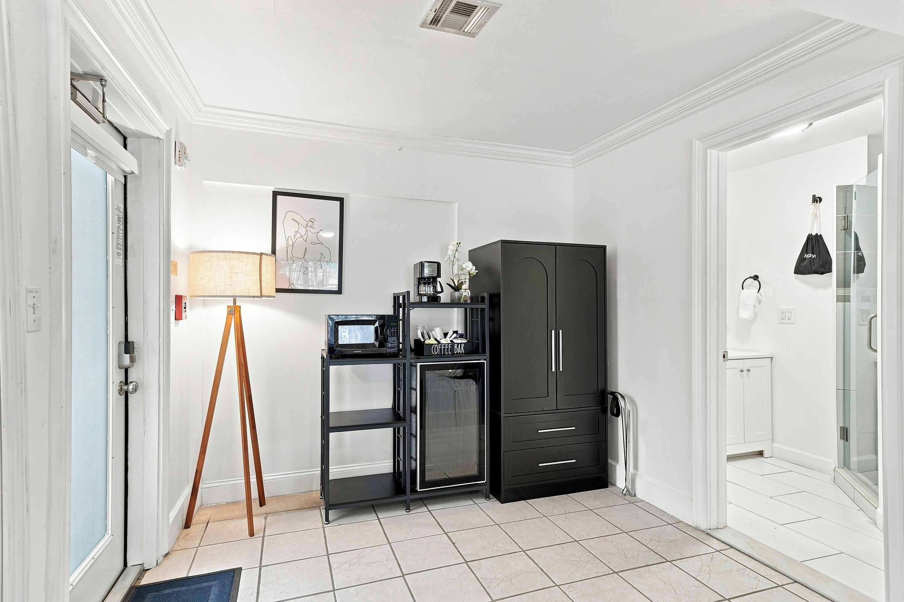 A compact room with a kitchenette, a coffee machine, a microwave, and a cabinet.