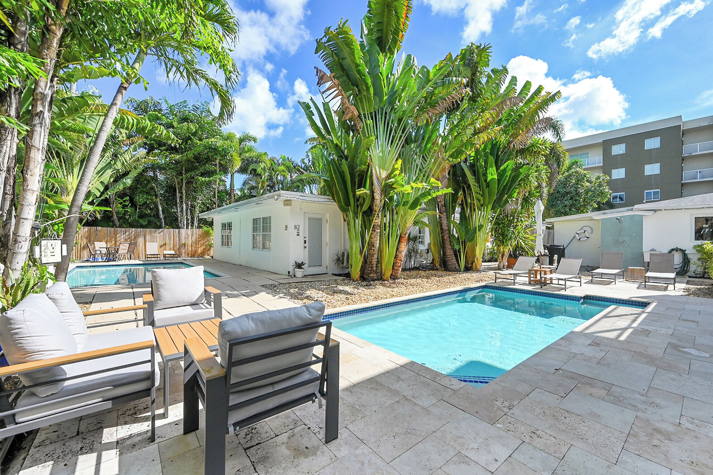 Un jardin avec une piscine, des chaises longues et un petit bâtiment.