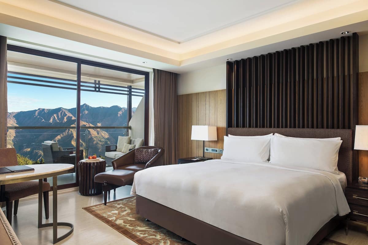Une chambre d’hôtel avec un grand lit, un bureau, une chaise et une vue sur les montagnes.