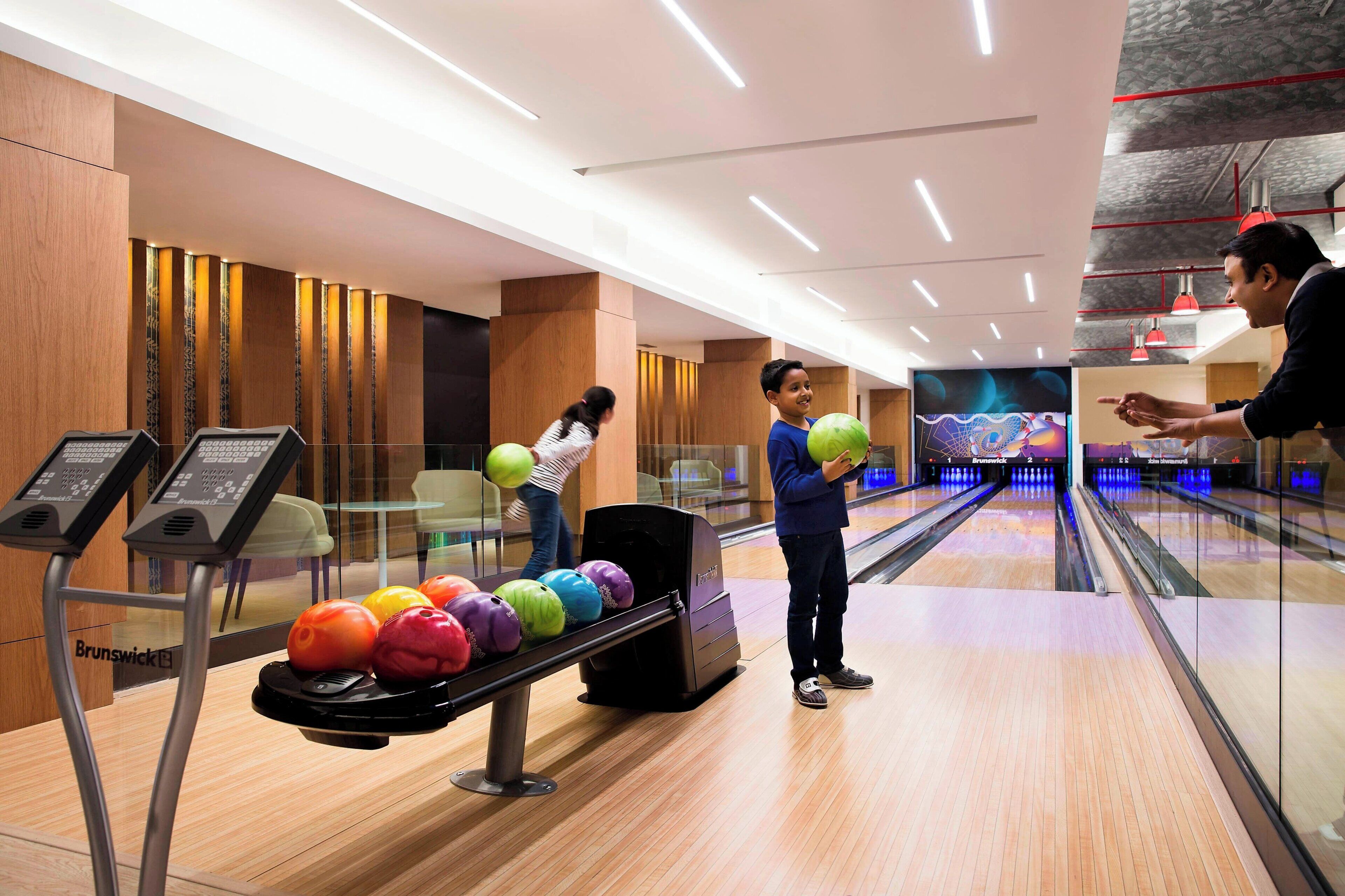 Une salle de bowling au design moderne, avec un plancher en bois et une piste de bowling agrémentée de quilles colorées.