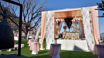 Montaje para un evento al aire libre con un fondo floral, mesas y una zona de bufé.