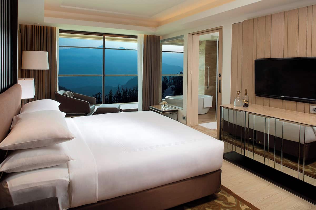Une chambre d’hôtel avec un grand lit, une télévision, un bureau et une vue sur les montagnes.