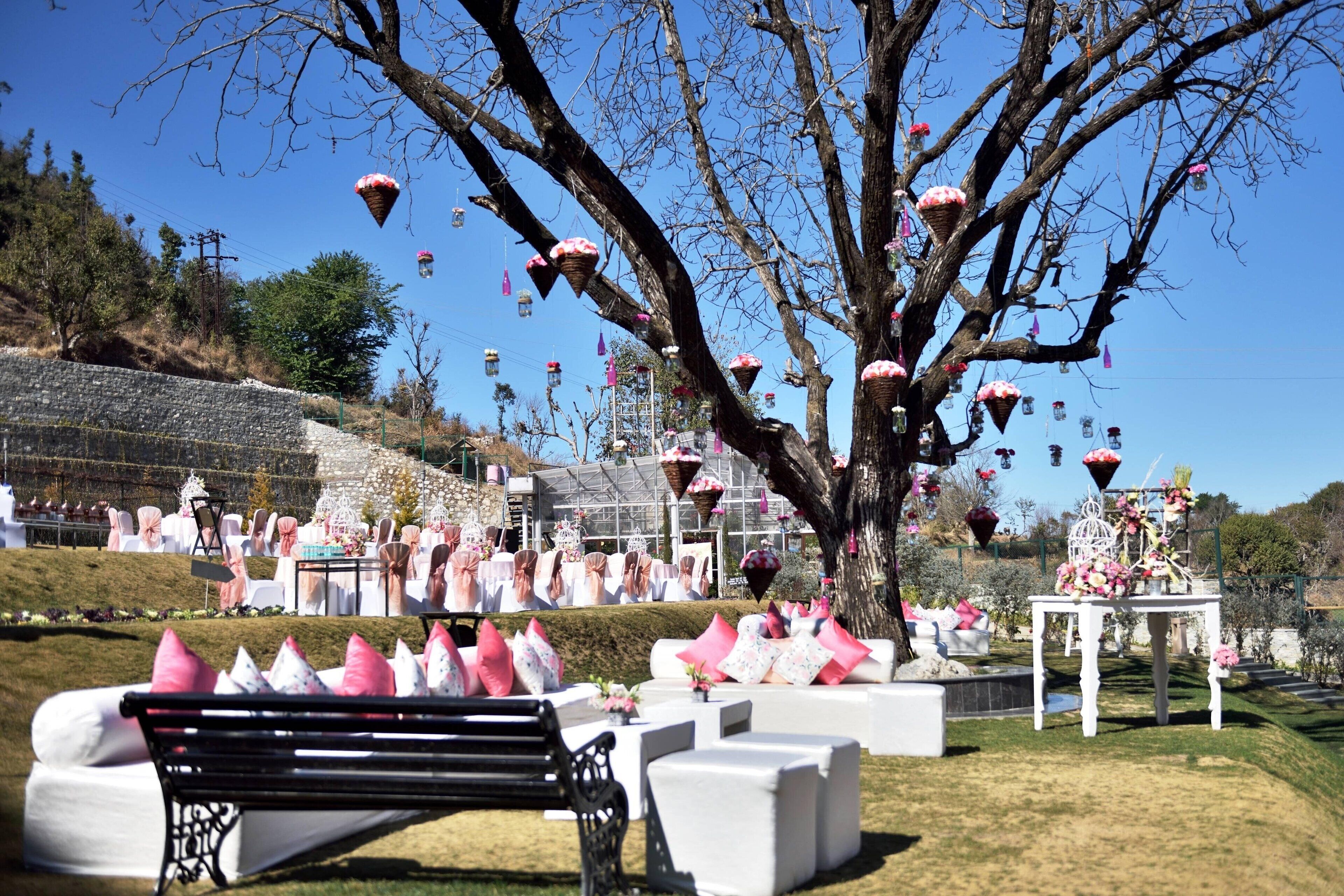 An outdoor event with a stage, white seating, and a tree with hanging decorations.