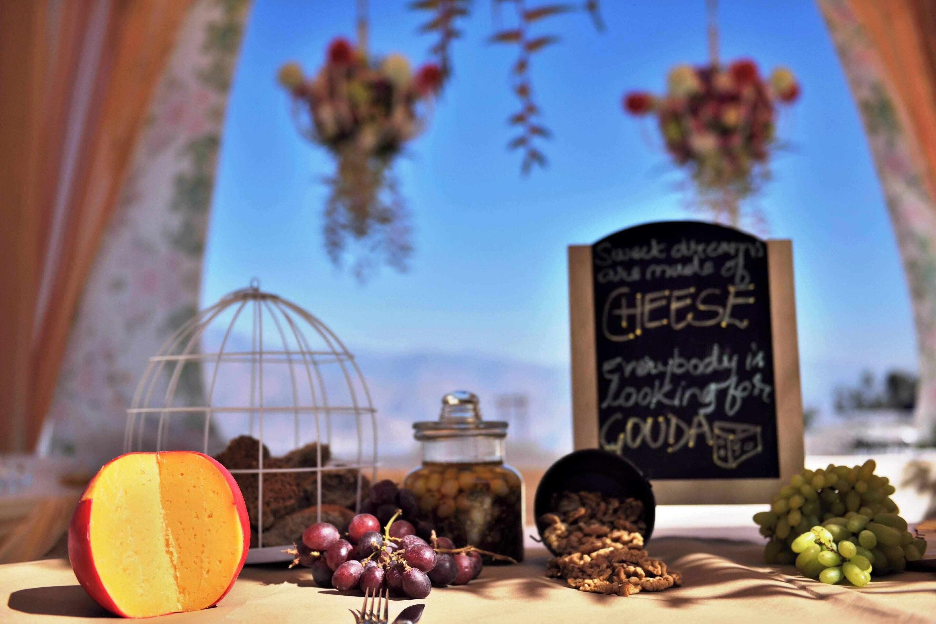 A table with a half-cut peach, grapes, nuts, and a chalkboard sign.