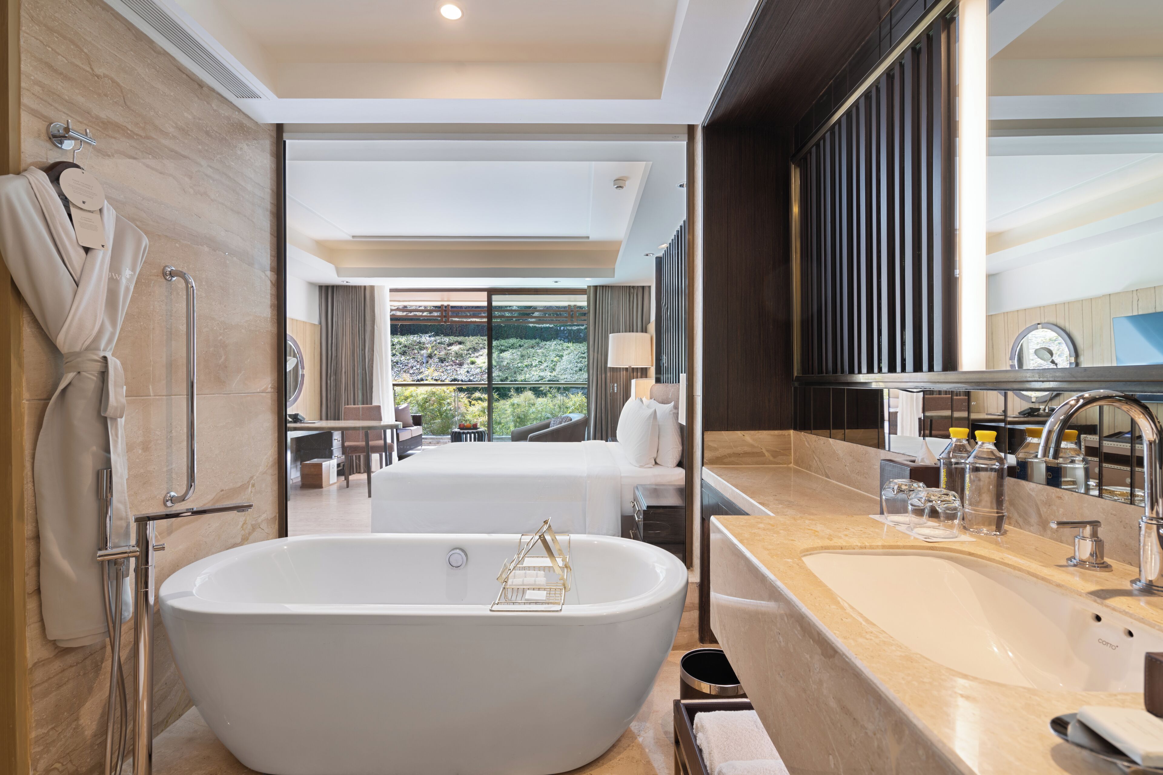 Un bagno moderno con una vasca freestanding, un ampio specchio e un lavandino.