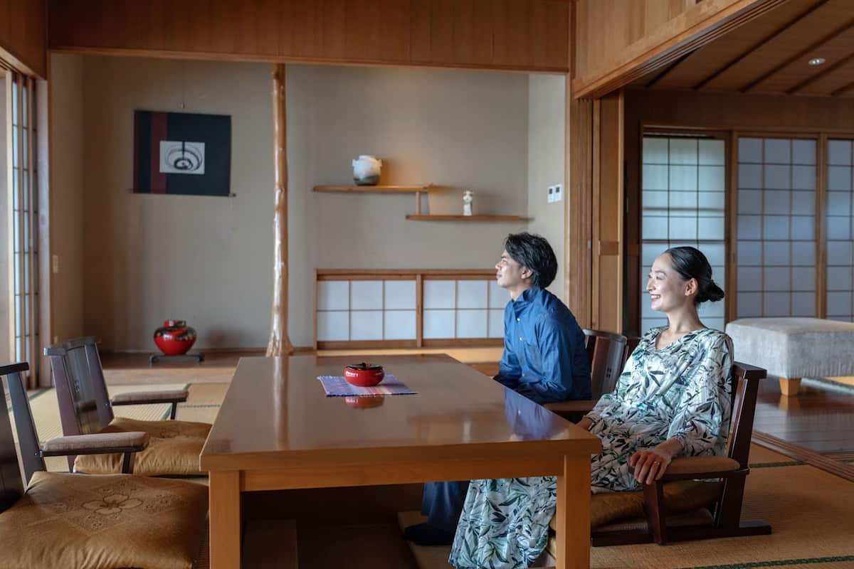 A traditional Japanese room with tatami flooring, a low wooden table, and a sliding door.