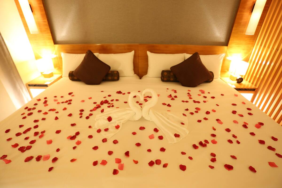 A hotel room with a large bed, two pillows, and a headboard.