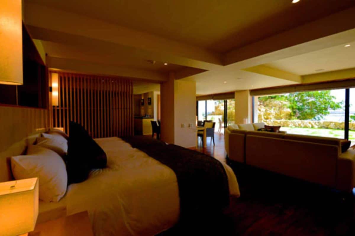 A hotel room with a large bed, a seating area with a view, and a dining area.