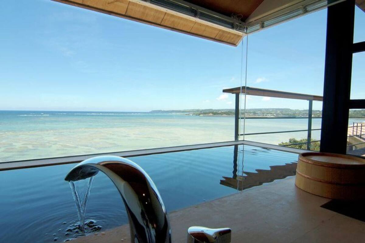 A modern infinity pool with a clear view of the sea and a wooden deck.