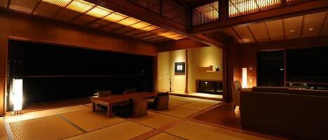 Una habitación tradicional japonesa con suelo de tatami, una mesa baja y un sofá.