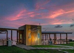 Un restaurante llamado 'PELICANOS' con terraza y vistas al agua.
