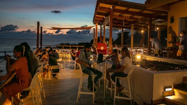 An outdoor dining area with tables and chairs, overlooking the sea. - Atami Escape Resort (Tamanique)