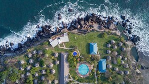 An aerial view of a coastal resort with a pool, a large building, and a rocky shoreline. - Atami Escape Resort (Tamanique)