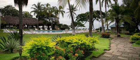 Et tropisk resort med swimmingpool, liggestole, palmer og velplejede haver.