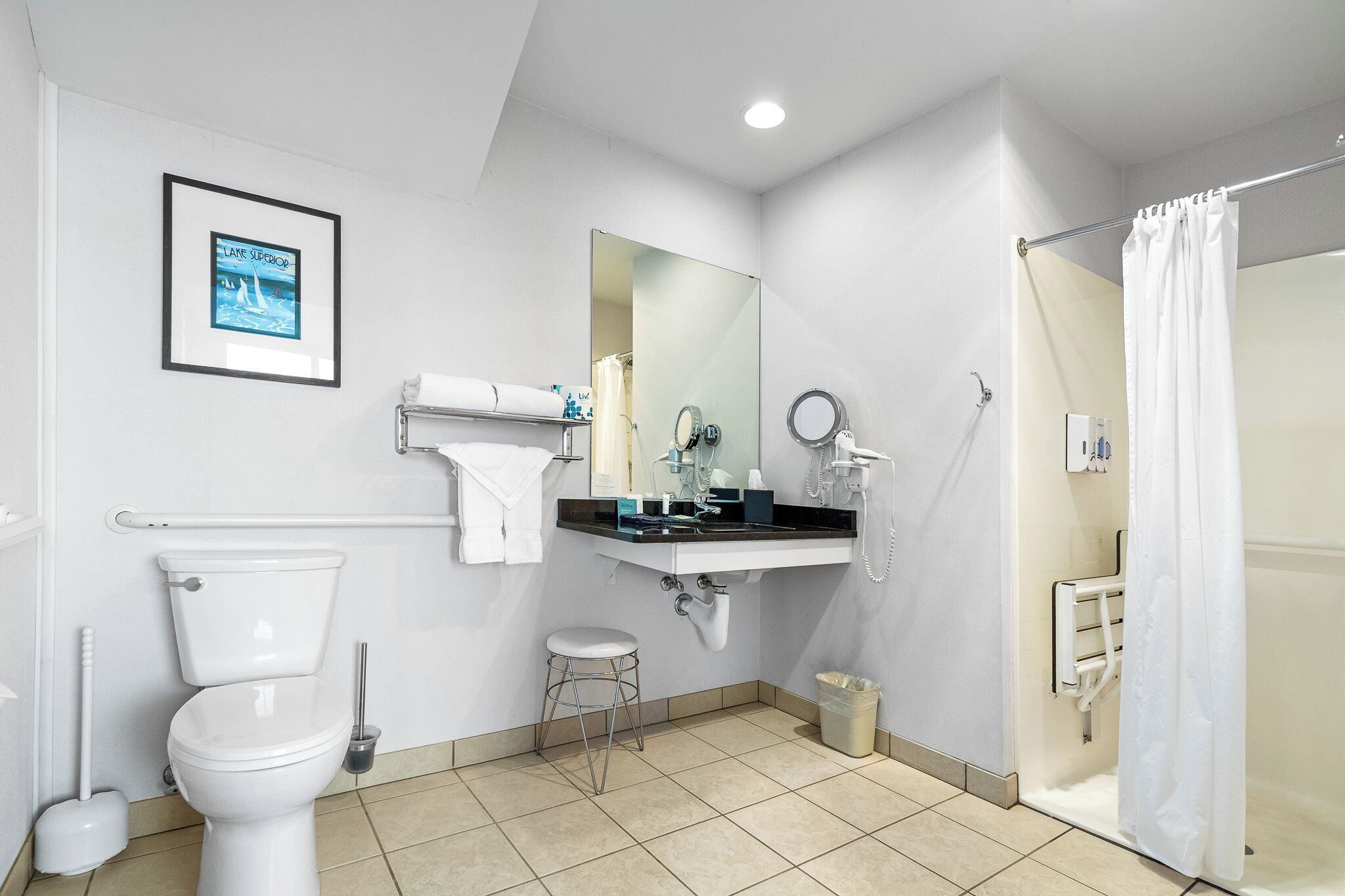 A modern bathroom with a toilet, sink, mirror, and shower.