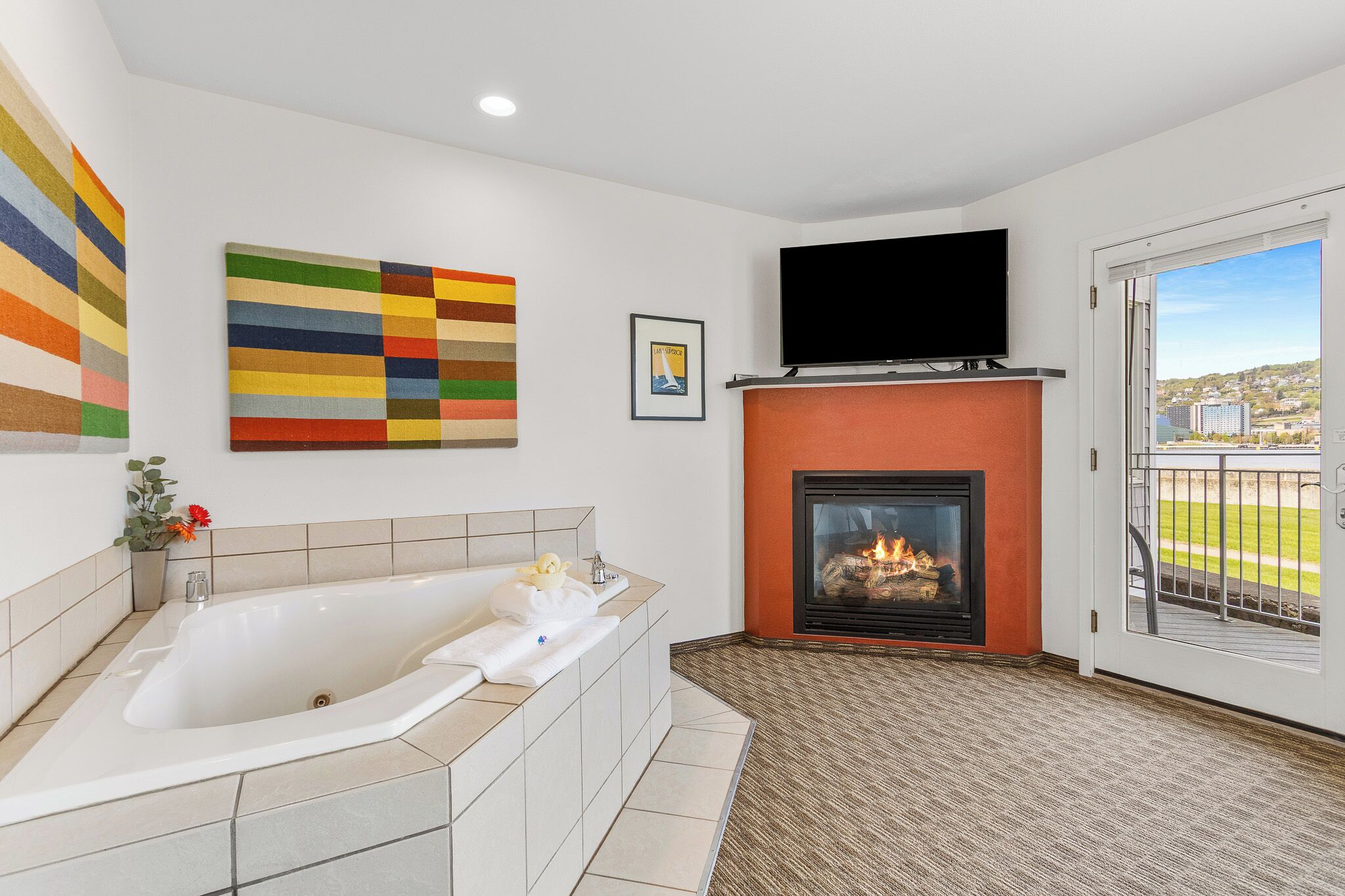 A bathroom with a bathtub, a fireplace, and a television mounted above it.