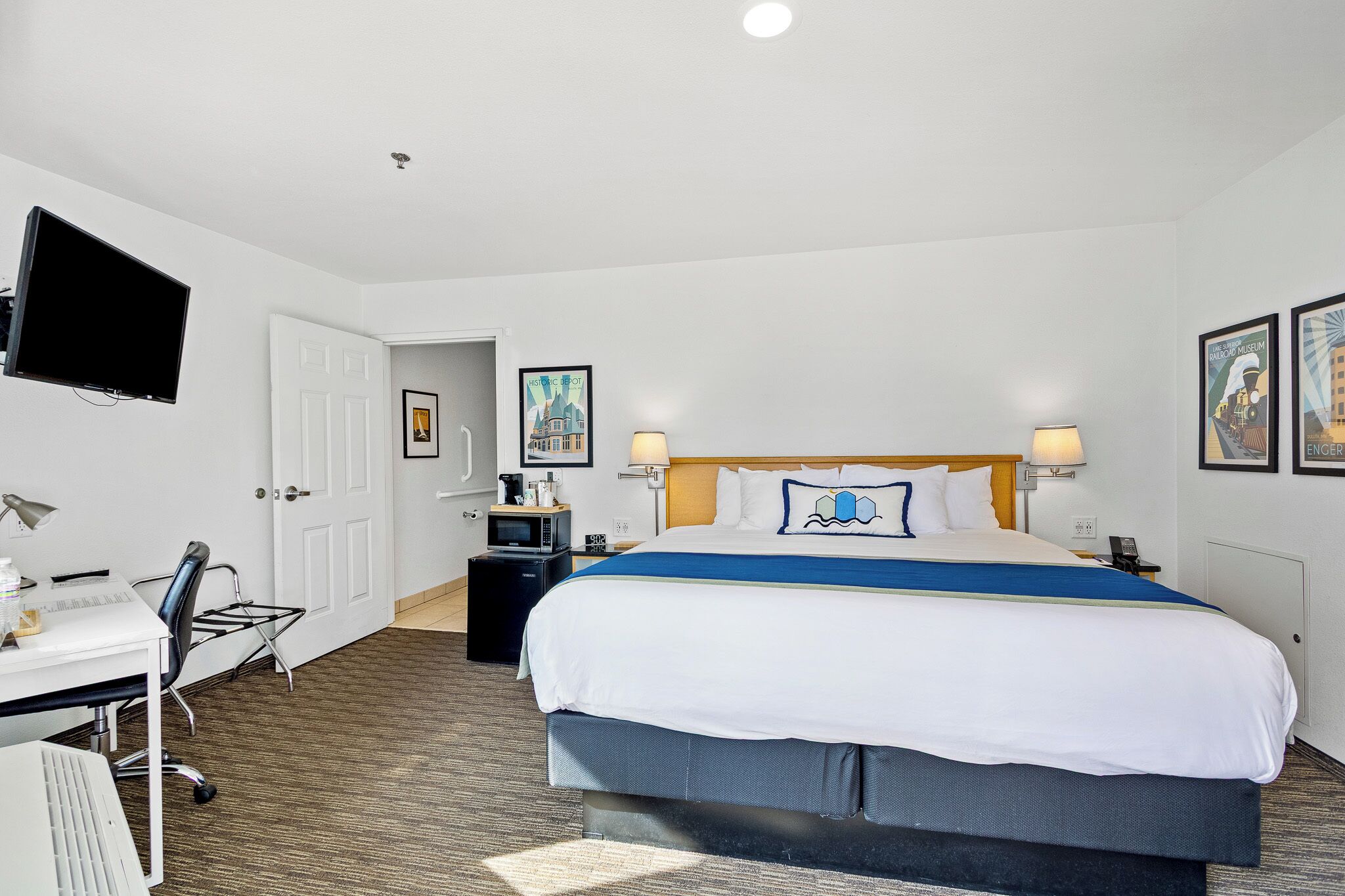 A hotel room with a bed, desk, chair, and a television.