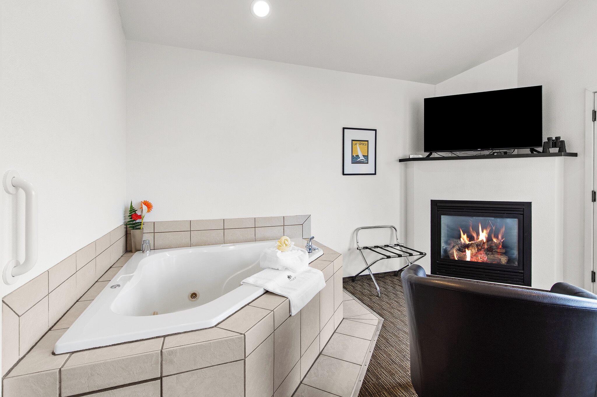 Un baño moderno con una bañera independiente, una chimenea y un televisor montado encima.