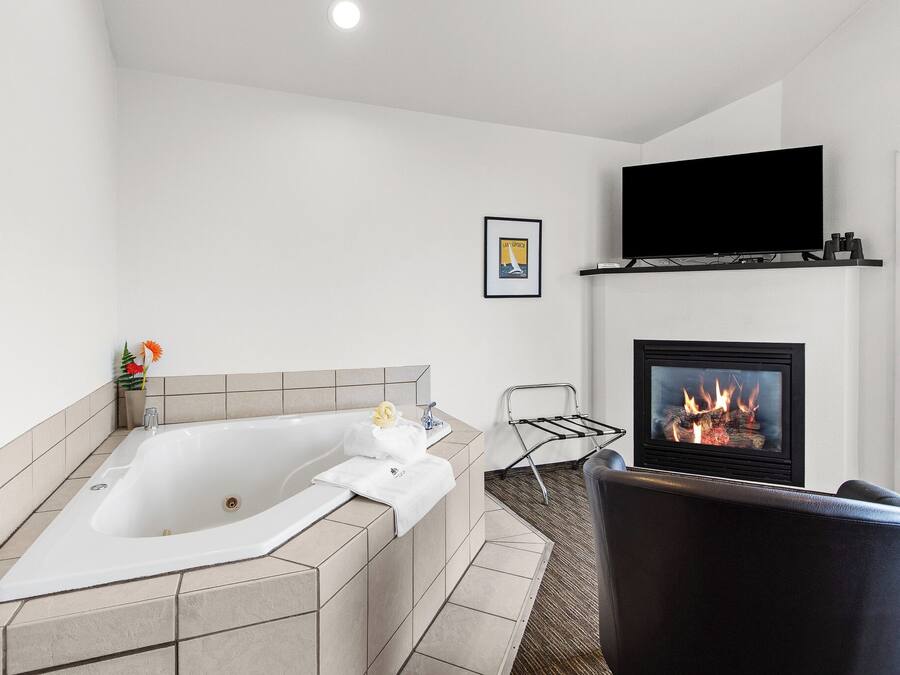 A modern bathroom with a freestanding bathtub, a fireplace, and a television mounted above it.
