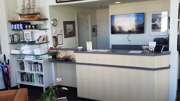 A reception desk with a television displaying a welcome message, a clock, and a framed picture.