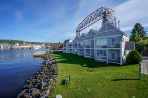 Un hotel a la vora del mar amb un moll, una grua i un litoral rocos.