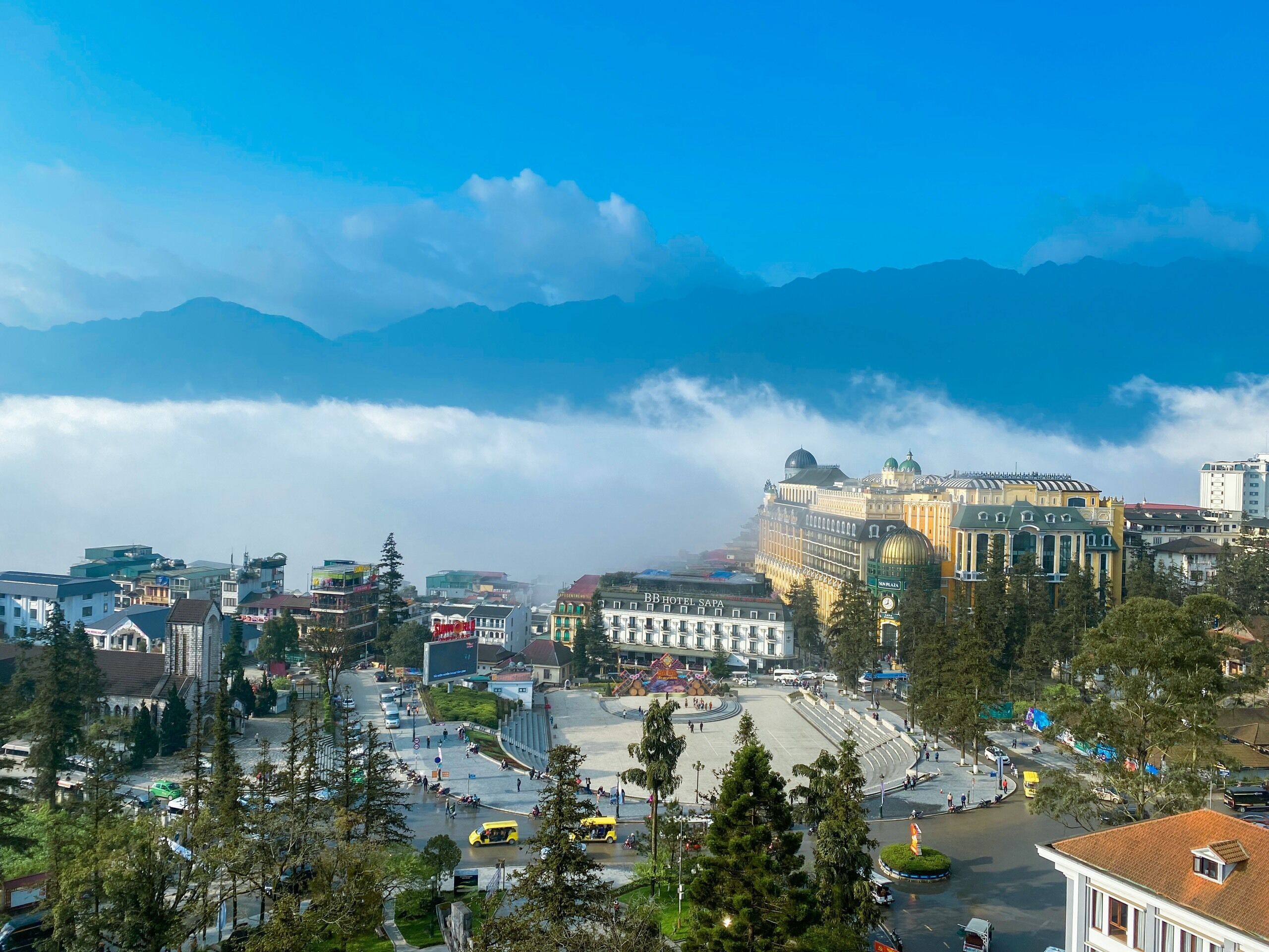 A hotel with a large central courtyard, surrounded by buildings and a mountainous backdrop.