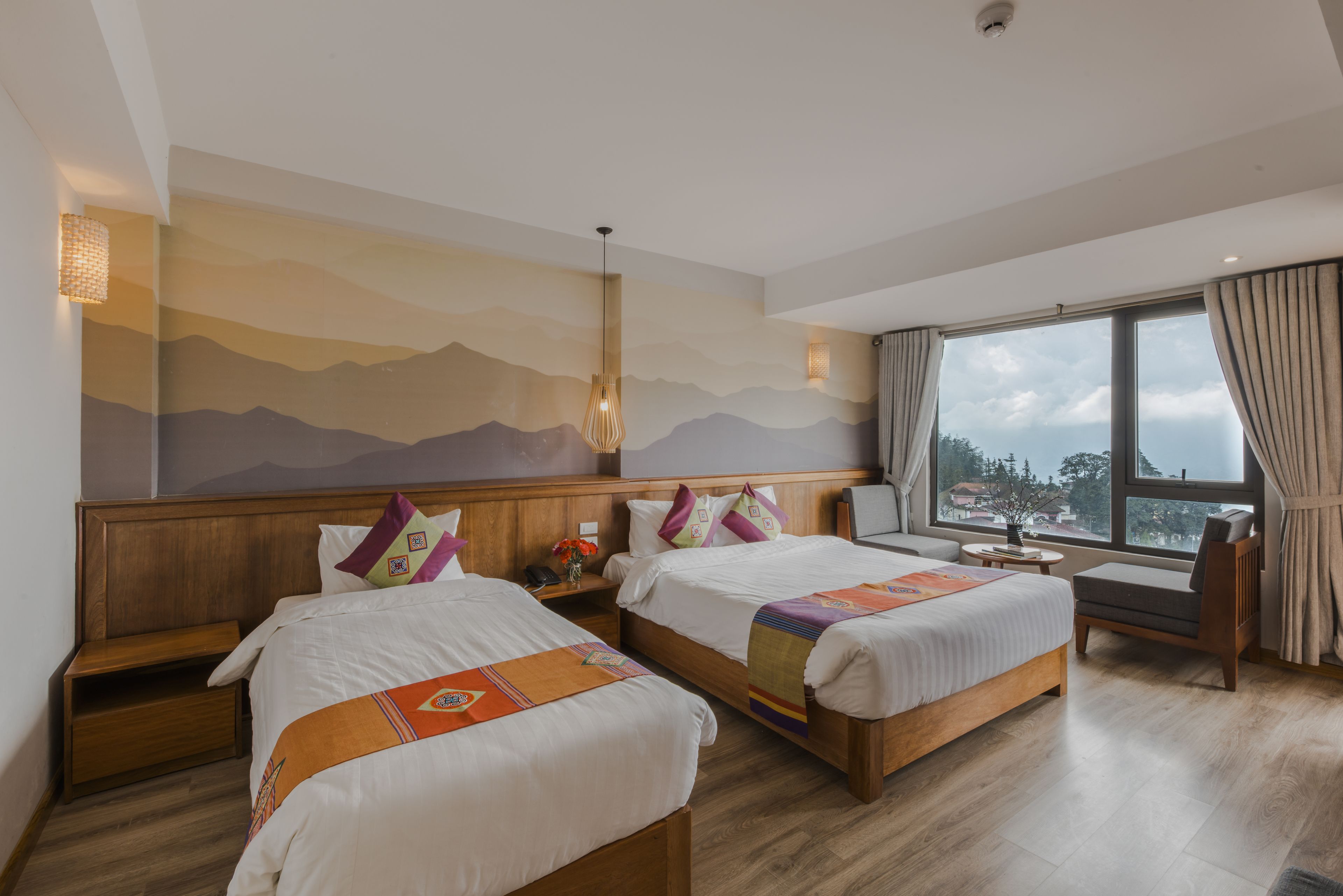 Een hotelkamer met twee bedden, een groot raam met uitzicht en een muurschildering.