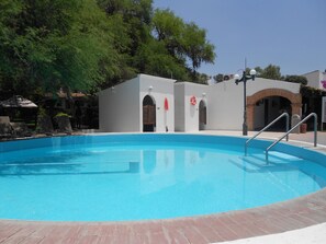 A swimming pool with a brick deck, surrounded by a white building with arched doorways and a red lifebuoy. - Hotel Hacienda Taboada (San Miguel de Allende)