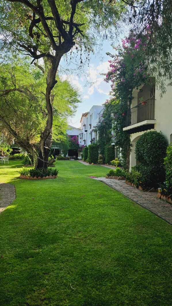 A well-maintained garden with a pathway leading to a building with balconies.